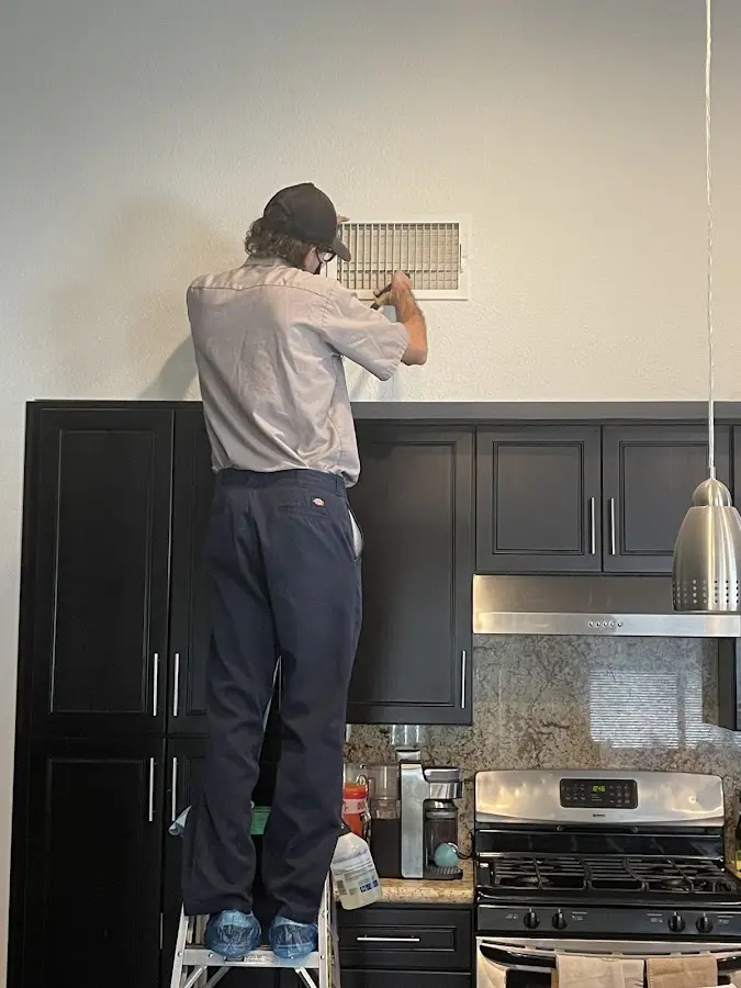 Technician inspecting an air vent during HVAC service in Wilmington Manor